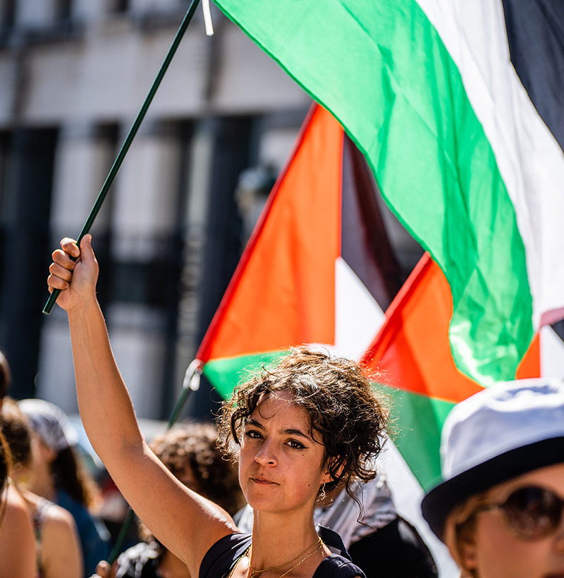 Een jonge vrouw houdt een Palestijnse vlag vast tijdens een solidariteitsbijeenkomst met Palestina. 