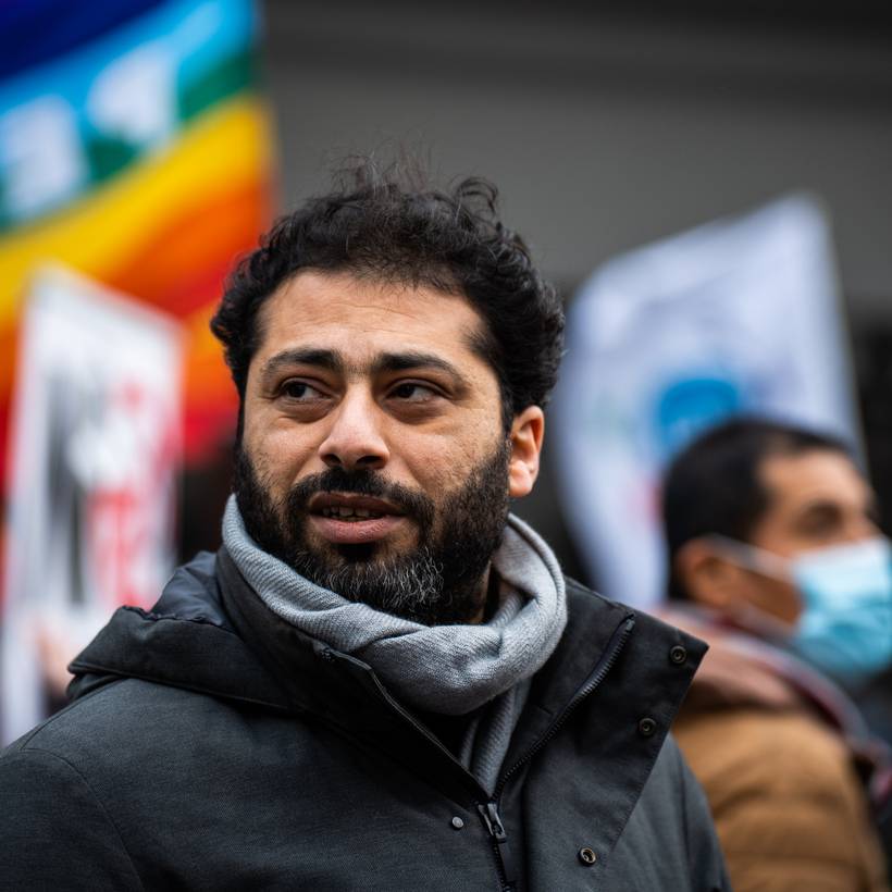 Nabil Boukili kijkt ernstig in de verte. Op de achtergrond wappert een vredevlag.