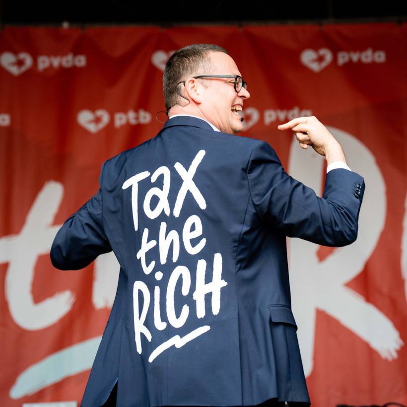 Raoul Hedebouw toont tijdens zijn toespraak zijn vest waar 'tax the rich' op geschreven staat 