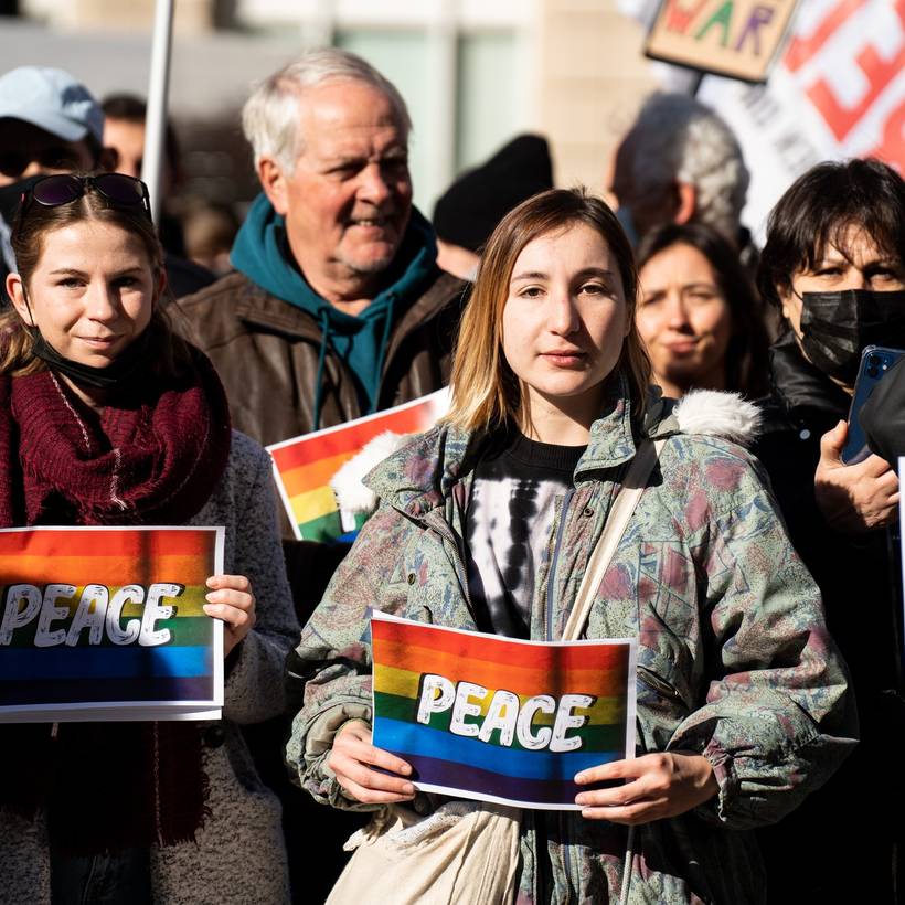 Vredebetogers met bordjes waar 'peace' op staat. Jonge vredesactivist