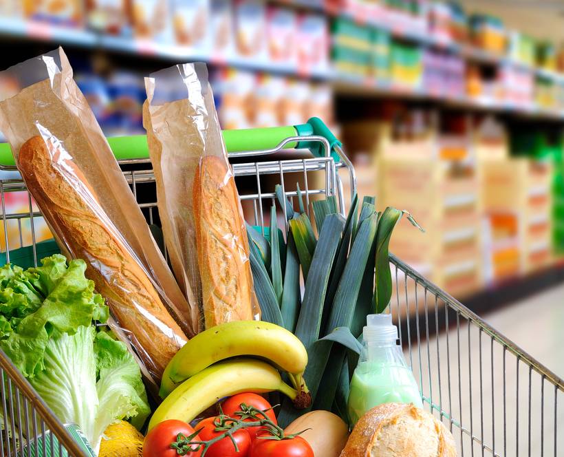 Un caddie dans un supermarché, contenant principalement des produits alimentaires.