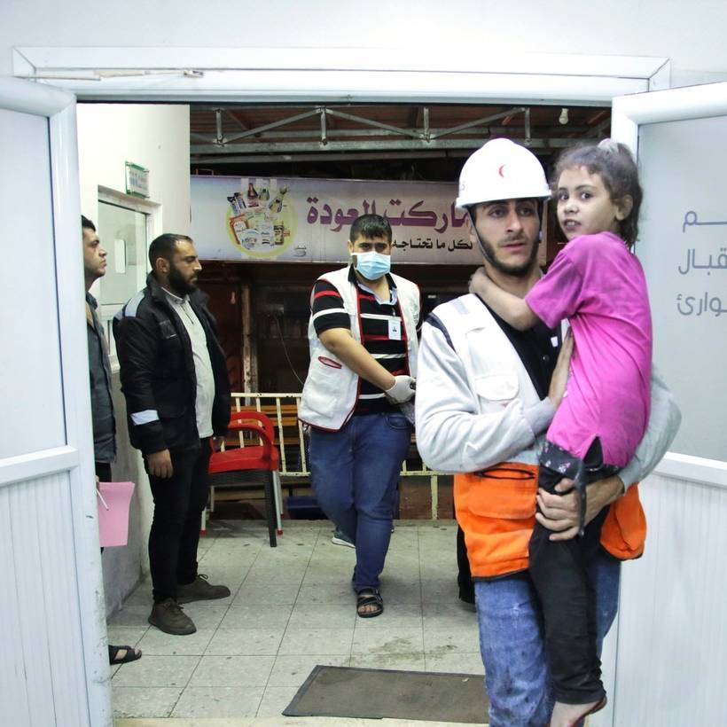 Een zorgverlener van het Al-Awda-ziekenhuis in Gaza draagt een meisje in zijn armen.