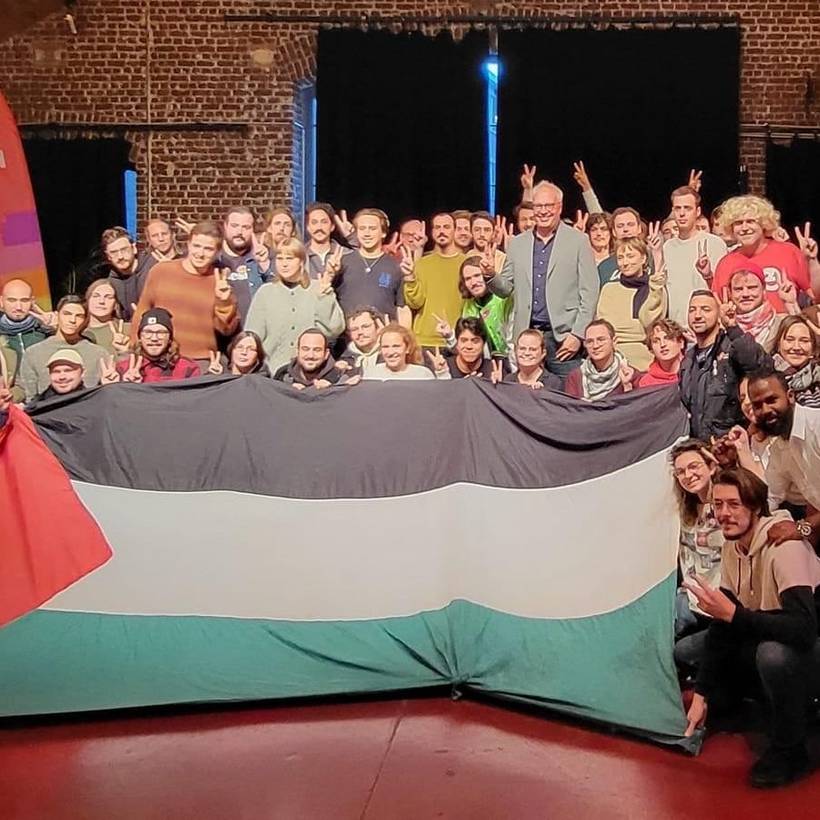 Peter Mertens en een groep jonge PVDA-leden poseren achter de Palestijnse vlag. 