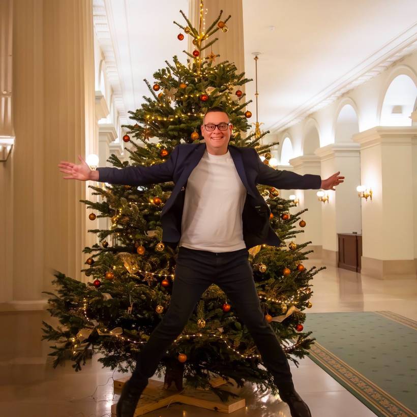 Raoul Hedebouw, président du PTB, saute devant un sapin décoré pour les fêtes.