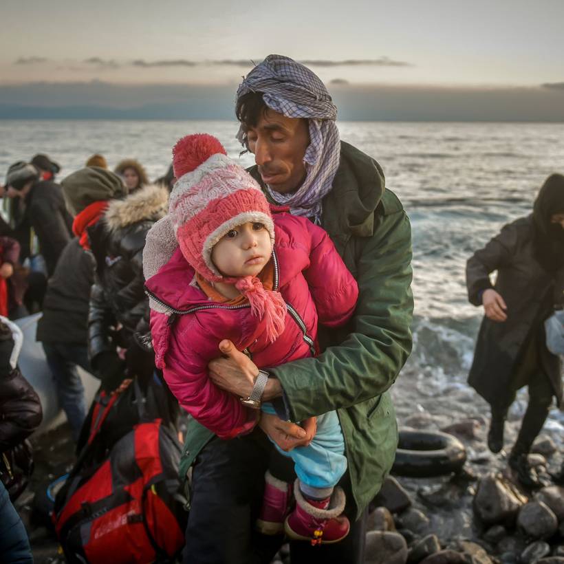 Des migrants s'entraident au bord de la mer.