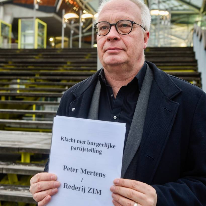 Peter Mertens staat voor het Antwerpse justitiepaleis en toont de klacht die hij indient