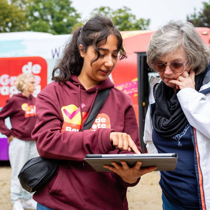 Een vrouw vult de Grote Bevraging in aan de campagnebus van de PVDA.