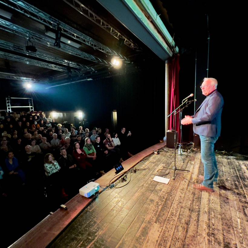 Peter Mertens sur un podium dans une salle comble.