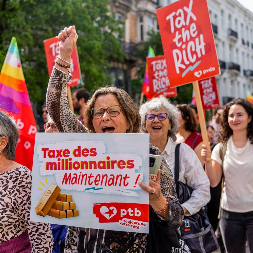 Une femme porte une pancarte disant ‘taxe des millionaires maintenant !'