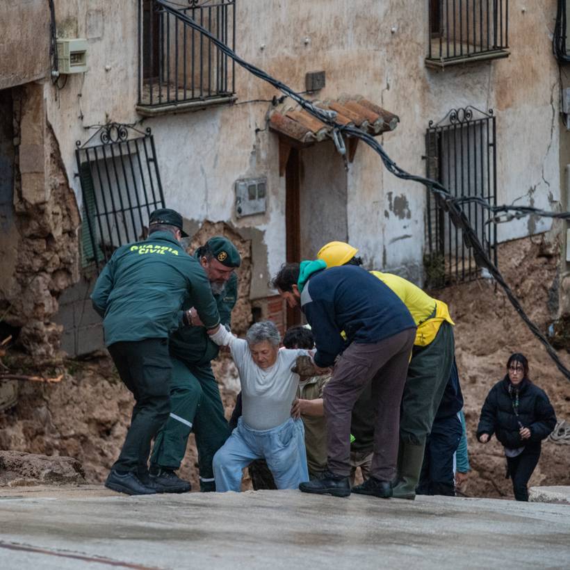 Des habitants d'un village en Espagne aident une femme âgée à sortir des décombres causés par les fortes inondations.