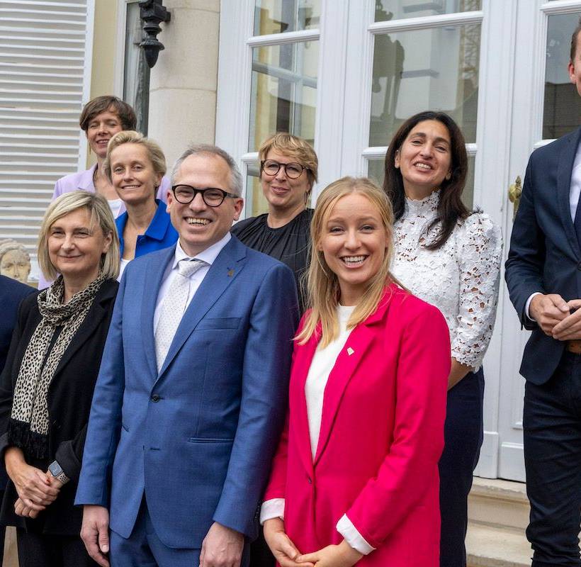 Groepsfoto van de Vlaamse regering met allemaal lachende gezichten