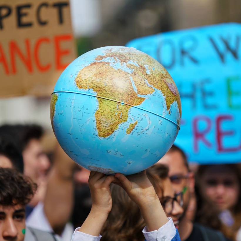 Handen dragen een wereldbol tijdens een klimaatprotest.