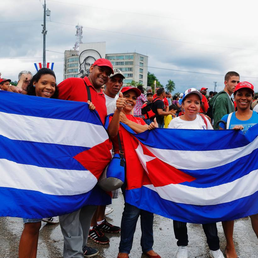 Un groupe de personnes souriant brandissent des drapeaux cubains