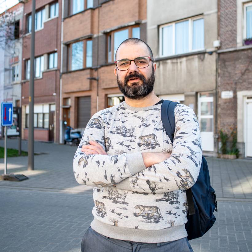 Un homme dans la trentaine pose dans la rue, les bras croisés