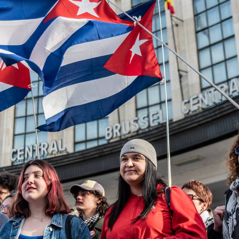 Groupe de jeunes avec des drapeaux cubains derrière eux lors de l'action "Pas touche à Cuba" à Bruxelles le 7 février 2026