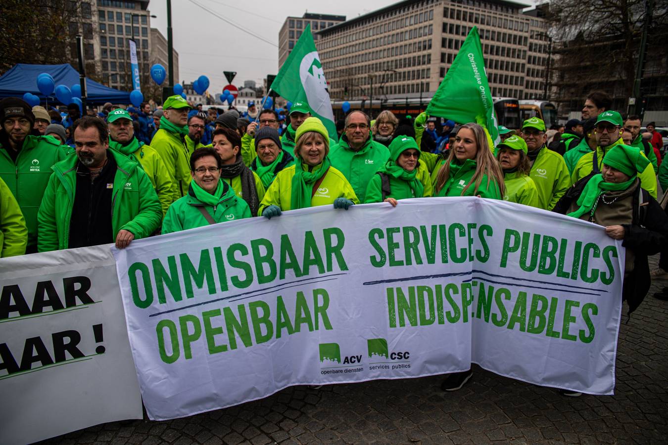 Des syndicalistes de la CSC derrière une banderole "services publics".