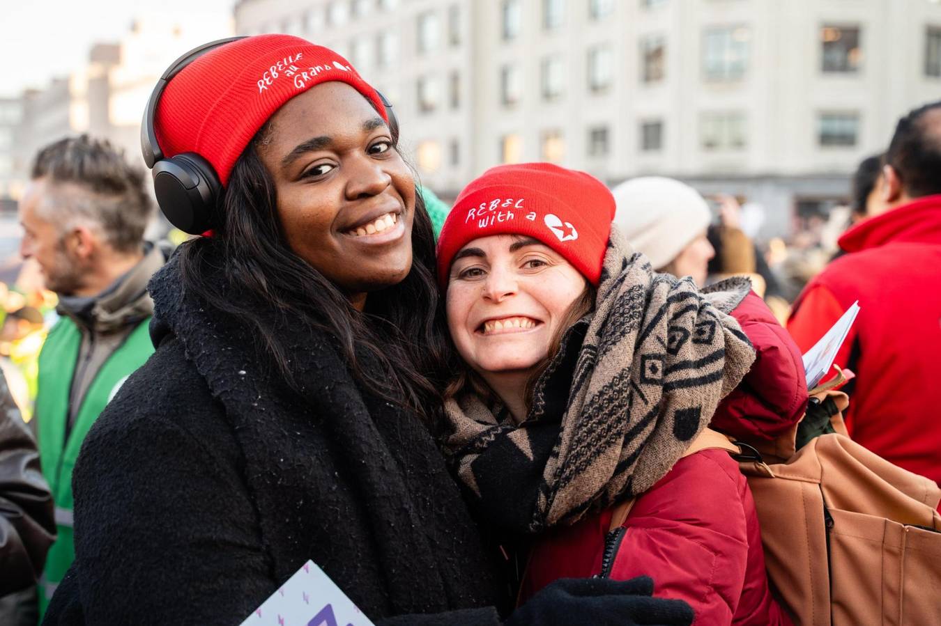 Een zwart en wit meisje die lachen naar de camera met PVDA-mutsen