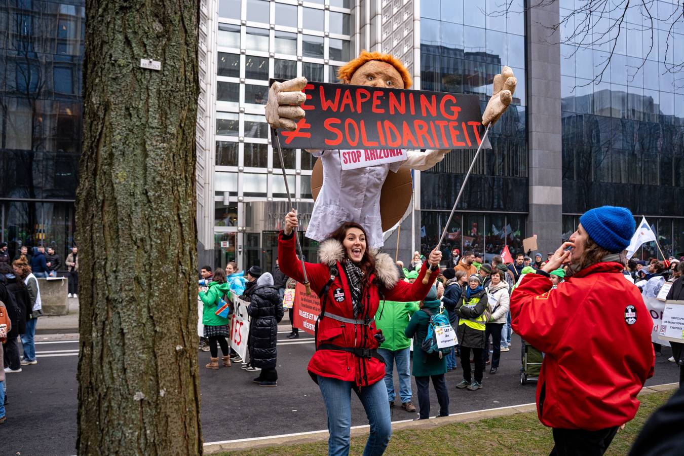 vakbondsbetoging 13 februari: vrouw draagt een bord “Bewapening is geen solidariteit"