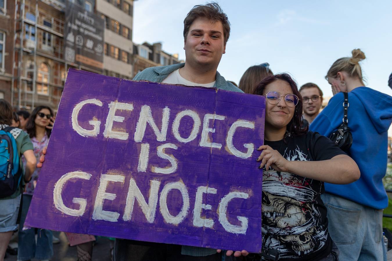 Beeld van op de manifestatie in Leuven tegen seksueel geweld, jonge man met een bord āGenoeg = genoegā