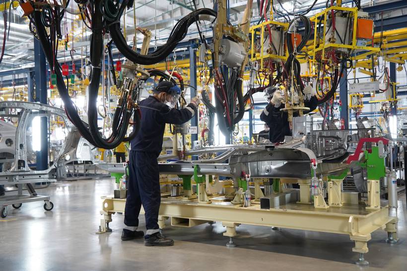 Jonge man werkt aan een auto in een fabriek.