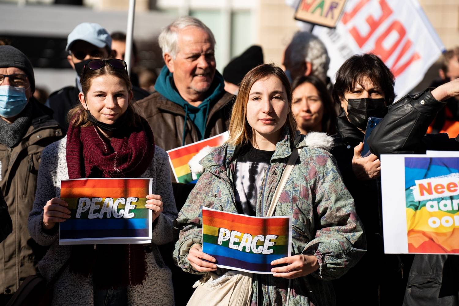 Vredebetogers met bordjes waar 'peace' op staat. Jonge vredesactivist
