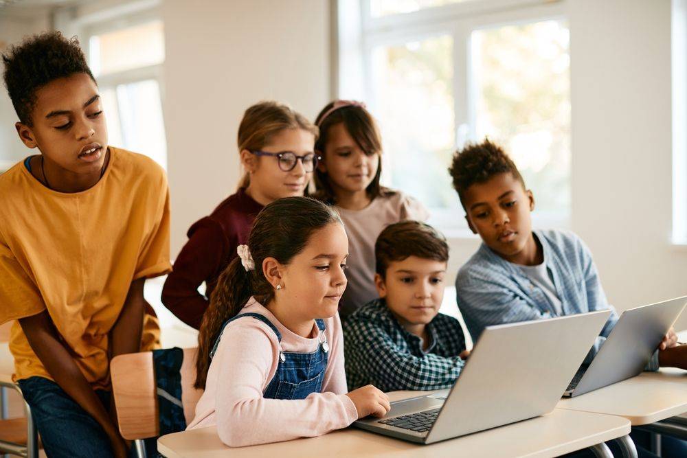 Des enfants regardent ensemble l'écran d'un ordinateur dans une salle de classe.