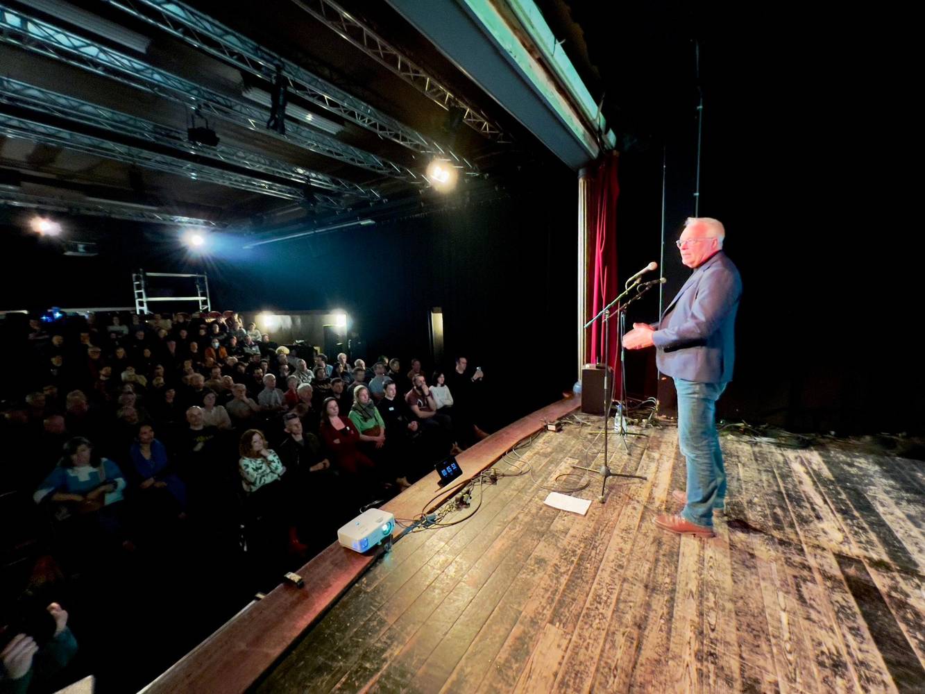 Peter Mertens sur un podium dans une salle comble.