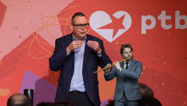 Raoul Hedebouw pendant son discours. Incrustation de Bouchez jouant du pipeau