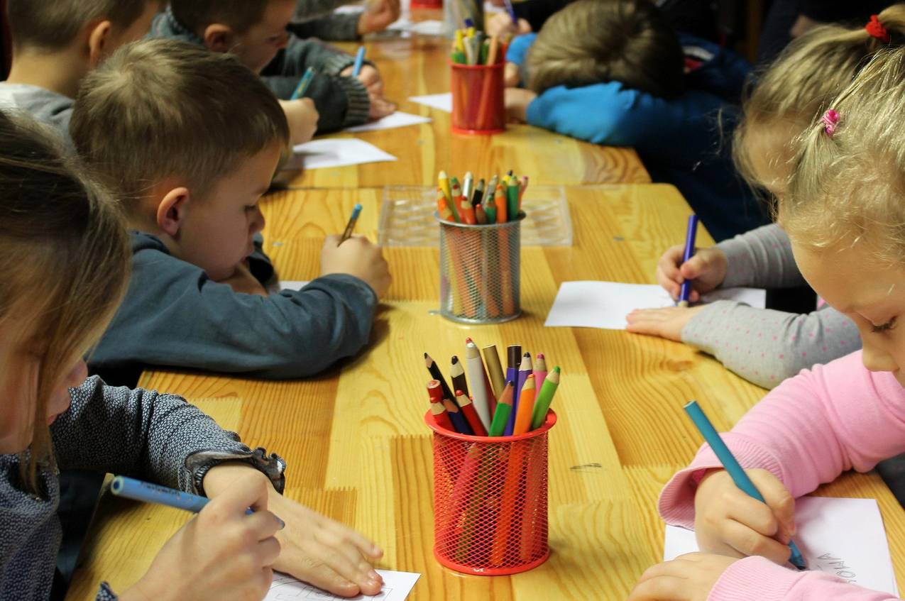 Jonge kinderen aan een lange tafel maken tekeningen