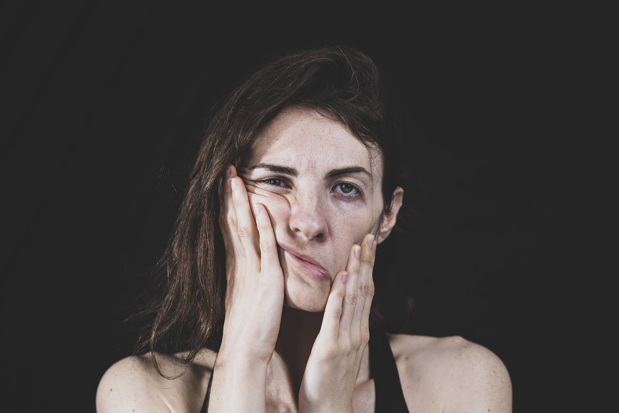 Beeld van een vrouw die haar gezicht vasthoudt om vermoeidheid/wanhoop uit te drukken